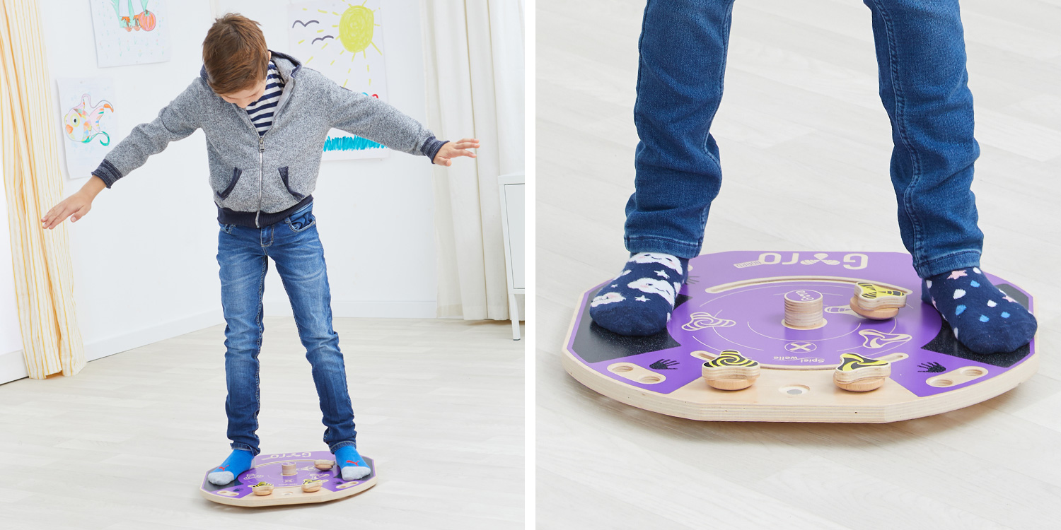 Junge balanciert auf dem Gyro-Board mit leicht gebeugten Knien. Mit Koordination und Motorik dreht er den Kreisel auf dem Board.