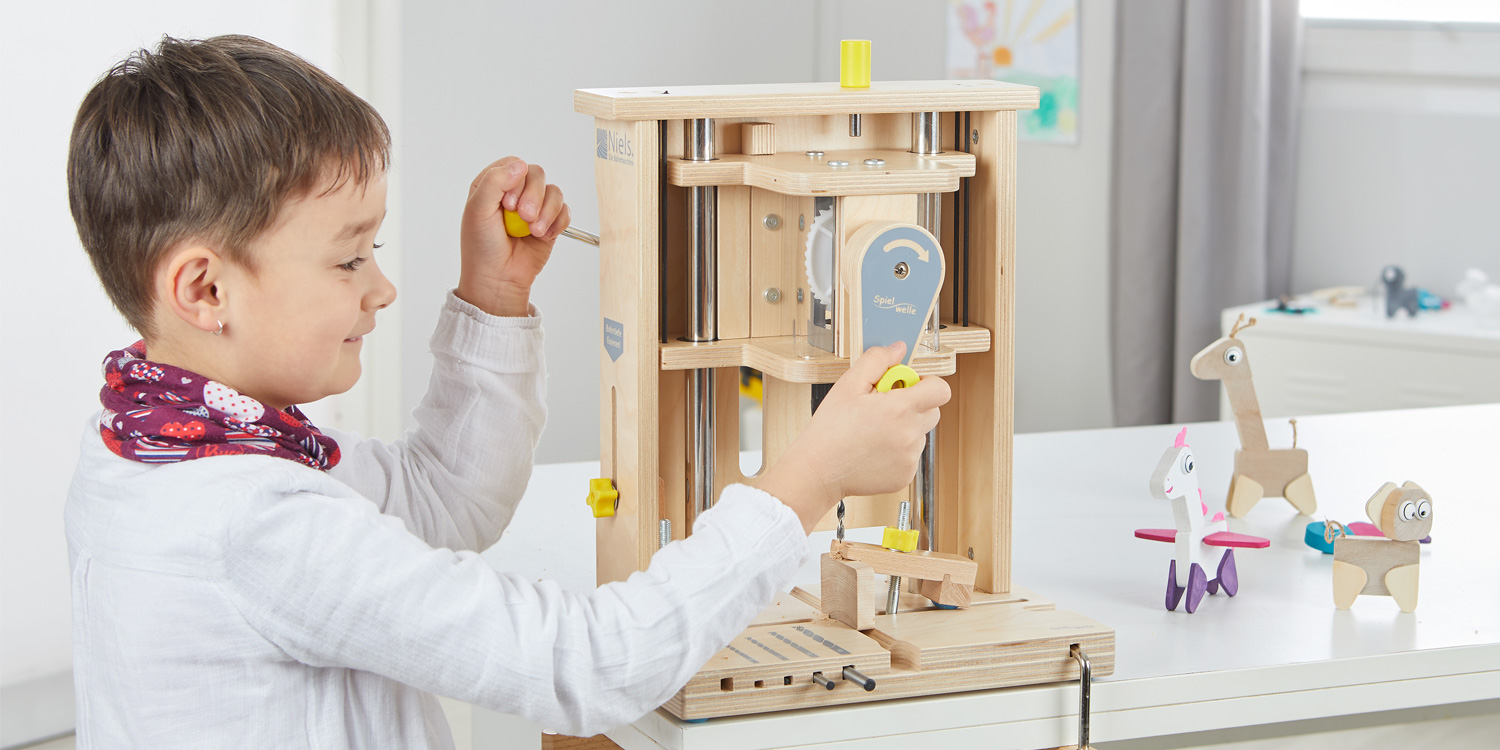 Ein Kind bohrt im Kindergarten mit der Bohrmaschine in Holz.